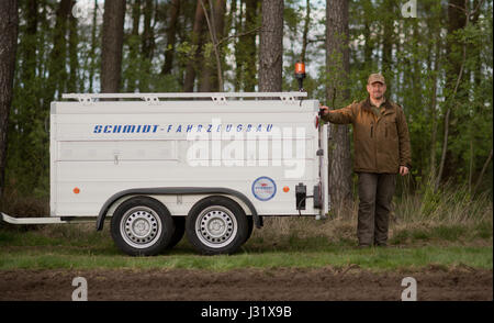 Wolf-carer Helge Stummeyer debout à côté de son chariot de transport pour les animaux blessés dans une forêt près de Vesbeck près de Neustadt am Ruebenberge, Allemagne, 20 avril 2017. Stummeyer gère une grande remorque de transport pour les animaux sauvages, qui a également été acheté pour la sécurité du transport aérien des loups. Photo : Julian Stratenschulte/dpa Banque D'Images