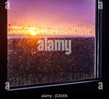 Coucher du soleil à la pluie dans la fenêtre Banque D'Images