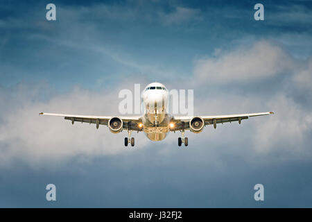 Vue de face d'un grand jet avion au décollage sur fond de ciel bleu nuageux Banque D'Images