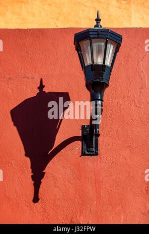 La rue noire de lumière sur un mur rouge jette une ombre forte à Campeche, Mexique Banque D'Images