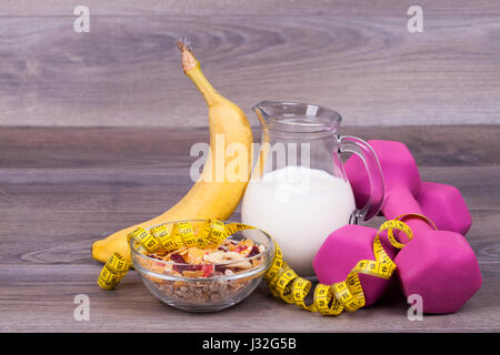 Régime alimentaire et de remise en forme avec poids concept, des yaourts, du muesli et banane sur un fond de bois Banque D'Images