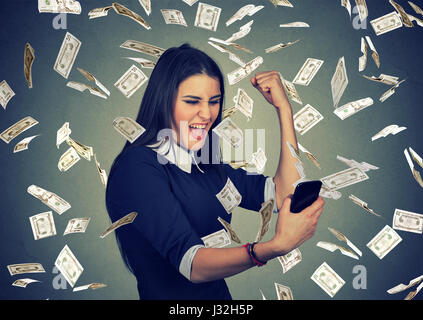 Happy woman réussie à l'aide des smart phone heureux sous la pluie l'argent dollars tomber vers le bas Banque D'Images