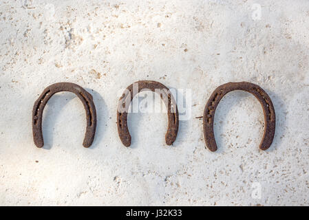 Trois anciens fers rouillés accroché sur un mur blanc, symbole de chance Banque D'Images