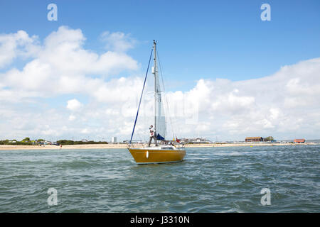 Petit yacht de quitter le port de Langstone. Personne debout sur le pont, les voiles de fraisage. Banque D'Images