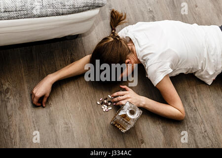 Ivre ou intoxiqué jeune femme avec bouteille d'alcool et des pilules, whisky et les drogues, la toxicomanie Banque D'Images