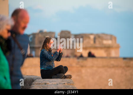 ALGHERO, ITALIE, 1 mai 2017 - Une fille prend des photos à la vue des anciens murs d'une fortification à Alghero au coucher du soleil, de l'Italie 1 mai 2017 Banque D'Images