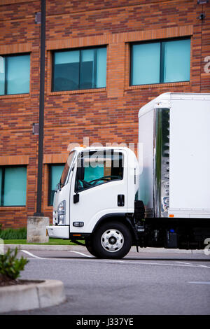 Petit camion semi petite classe sans capot moteur avec une petite boîte d'attente de la remorque pour le conducteur debout près d'un entrepôt de la brique. Banque D'Images