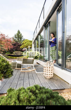 Femme à la terrasse porte avec une tasse, coodo style de vie moderne, l'architecture moderne en Allemagne du nord, Hambourg, Allemagne Banque D'Images
