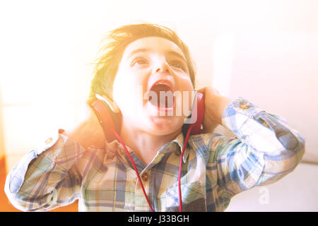 Funny enfant écoute de la musique avec des écouteurs dans une atmosphère familiale Banque D'Images