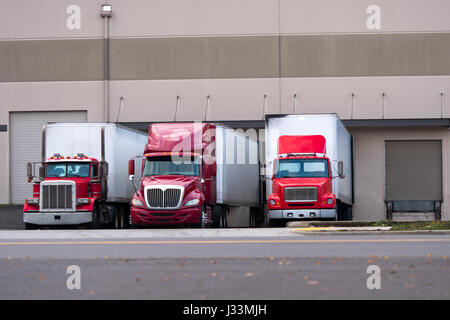 Trois fabricants de semi-camions rouges et diverses modifications, des anciens modèles classiques aux semi-camions aérodynamiques modernes avec remorques de camionnettes sèches Banque D'Images