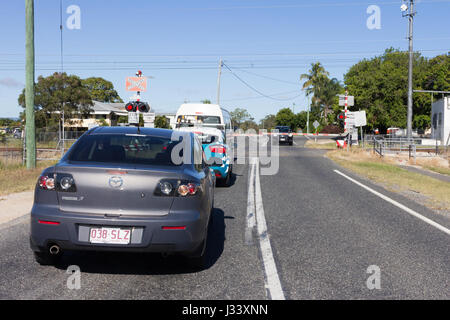 L'attente à la circulation contrôlée barrière de passage à niveau d'un train, Queensland, Australie Banque D'Images