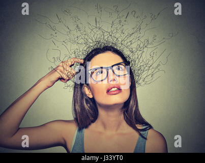 Closeup portrait jeune femme se gratter la tête, pensant à rêver avec la fonte du cerveau en lignes d'interrogation jusqu'à isolé sur fond gris Banque D'Images