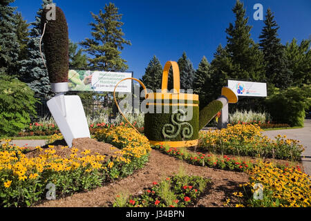 Sculpture végétale vivante d'une truelle de jardin et arrosoir créé sur des formes en maille de métal remplies de terre et plantées avec diverses plantes et herbes Banque D'Images