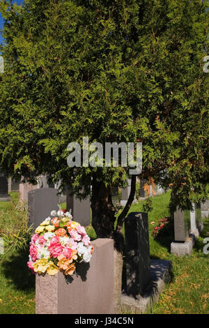 Bouquet de fleurs en soie et pierres tombales au cimetière Notre-Dame-des-Neiges à l'automne sur le mont Royal, Montréal, Québec, Canada. Banque D'Images