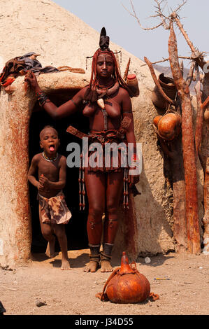 Femme Himba debout devant sa hutte près de Epupa Falls. Peuple Himba vit dans la région de Kunene, le nord de la Namibie dans la frontière de l'Angola Banque D'Images