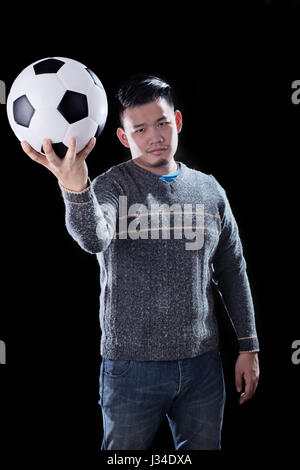 Young Asian man et ballon de soccer sur fond sombre pour utiliser football mania Banque D'Images