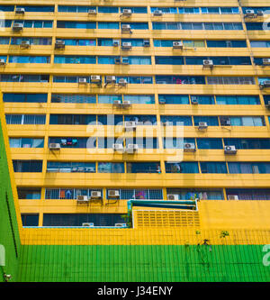 Le mur de bâtiment jaune avec windows et les conditionneurs d'air, peut être utilisé comme arrière-plan ou le modèle. Banque D'Images