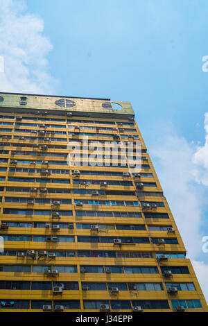 Le mur de bâtiment jaune avec windows et climatiseurs contre le ciel bleu, peut être utilisé comme arrière-plan ou le modèle. Banque D'Images