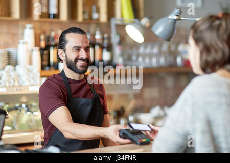 Barman et femme avec lecteur de carte et smartphone Banque D'Images