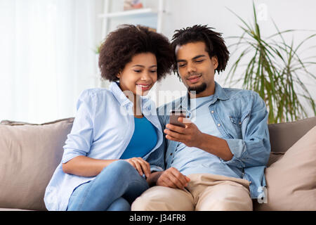 Couple heureux avec les smartphones à la maison Banque D'Images