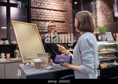 Barman et femme de payer par carte de crédit au café Banque D'Images