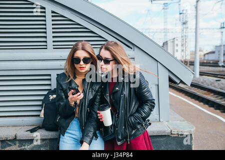 Deux femmes parlant dans la ville.de vie de plein air portrait de deux meilleurs amis hipster girls wearing veste en cuir élégant et des lunettes avec cofee, devenir fou et avoir beaucoup de temps ensemble