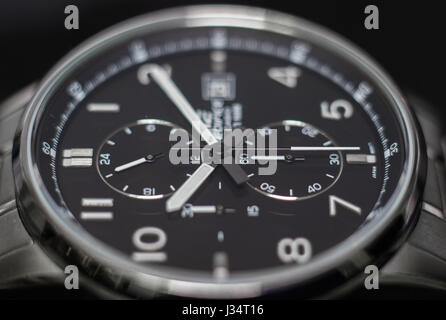 Gros plan d'une montre analogique en acier inoxydable, avec big black sphere, dans un fond noir, sur le côté. Banque D'Images