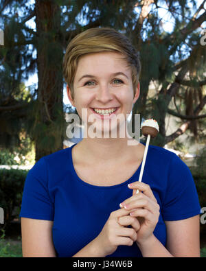 Parution de l'image modèle Young caucasian Teenage girl blonde tenant un gâteau cupcake pop sur un bâton pour traiter les parties fun Banque D'Images