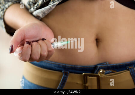 Femme avec une seringue d'injection sous-cutanée de l'abdomen de l'insuline à son ventre, à l'avant- diabète concept Banque D'Images