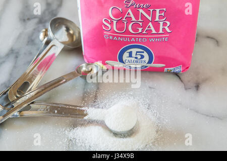 Une cuillère à café de blanc granulé dans une cuisine cuisine maison sur un comptoir en marbre Banque D'Images