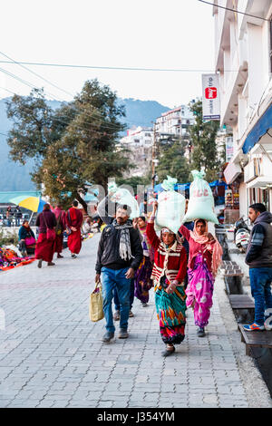 Le mode de vie des Indiens : les femmes locales de transporter de grosses charges lourdes dans des sacs sur leurs têtes dans la rue en McLeodGanj, Dharamshala, Himachal Pradesh, Inde Banque D'Images
