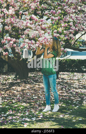 Jeune femme dans les tenues de l'odeur des fleurs de magnolia Banque D'Images