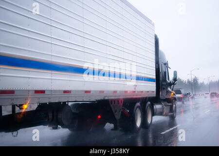 Big Rig semi truck avec réfrigérateur unité sur remorque frigorifique commercial industriel transports marchandises sur un multi-lignes autoroute avec revêtement brillant humide Banque D'Images