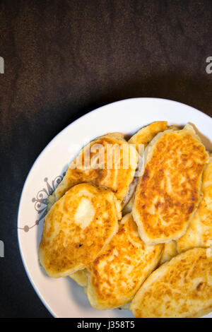 Les galettes de pommes de terre frites ruddy de nutriments sous forme de pâtisseries disposés sur une assiette et prêt à manger à la table de dîner de famille. Il fait référence à une main Banque D'Images