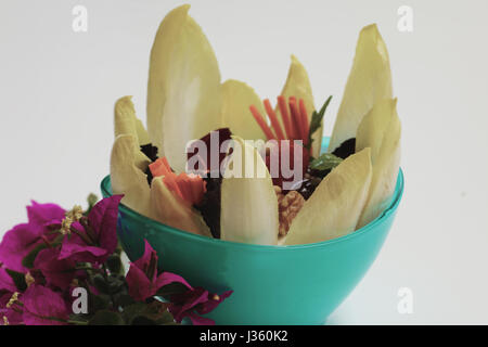 Salade sains et savoureux servis dans un bol bleu et garni de bougainvillées, isolé sur fond blanc Banque D'Images