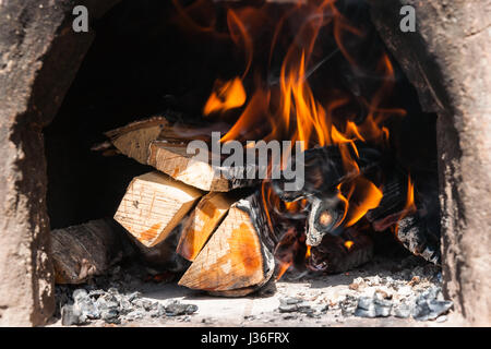 Le bois brûlant dans une poêle en argile vintage. Fire et un brin de fumée au-dessus du bois brûlé. Banque D'Images