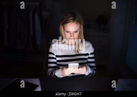 Femme avec ordinateur portable et smartphone, sms. Banque D'Images