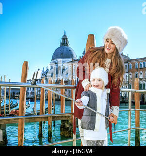 Un autre monde vacances. smiling trendy la mère et l'enfant les touristes à Venise, Italie en hiver en tenant à l'aide de bâton selfies selfies Banque D'Images