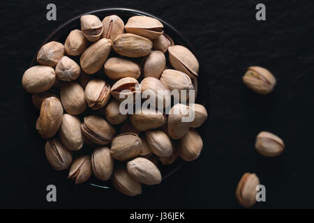 Pistaches grillées sur le fond sombre. La photographie alimentaire sombre. Vue d'en haut. Banque D'Images