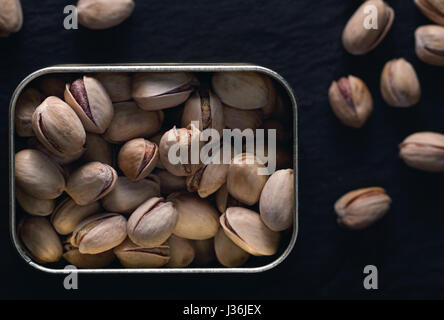 Pistaches grillées dans le métal sur le fond noir. La photographie alimentaire sombre. Vue d'en haut. Banque D'Images