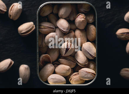 Pistaches grillées dans le métal sur le fond noir. La photographie alimentaire sombre. Vue d'en haut. Banque D'Images