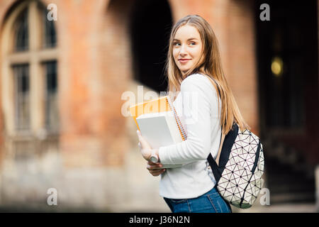 L'éducation, campus, l'amitié et de personnes concept - fille étudiante à l'extérieur avec sac et livres près de l'université Banque D'Images