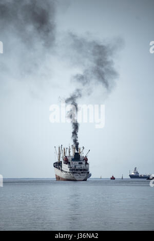 Fumée noire à l'entonnoir d'chalutier russe comme navire quitte le port. Banque D'Images