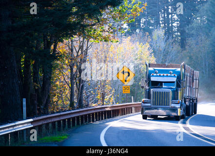 Grand professionnel américain bleu puissant semi truck age avec un deux remorques avec hauts côtés greffe, transporte les charges sur la route sinueuse de montagne par Banque D'Images