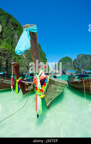 MAYA BAY, THAÏLANDE - 11 NOVEMBRE 2014 : bateaux longtail thailandais traditionnel décoré de bow bonne chance ceinturons flottent sur la rive de la baie de Maya. Banque D'Images