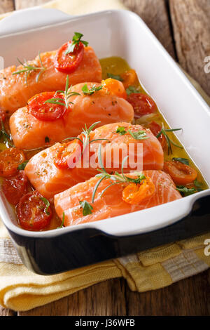 Mijoté de saumon et les tomates cerises dans l'huile d'olive dans un plat allant au four. La verticale Banque D'Images