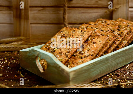 Libre de certains biscuits brun appétissant garni de graines différentes une pâle vert plateau en bois placé sur une table en bois Banque D'Images