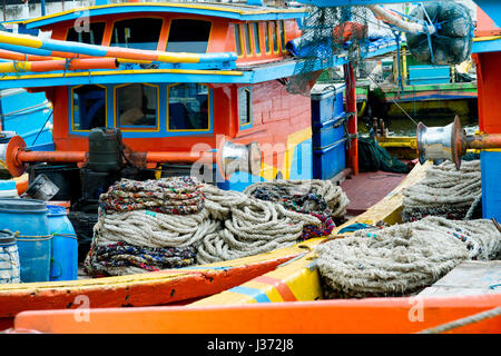 Vue rapprochée des treuils et câbles enroulés sur des bateaux de pêche colorés amarrés les uns à côté des autres Banque D'Images