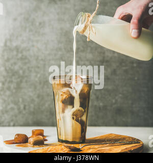 La main de l'homme de verser le lait au café latte froid cocktail Banque D'Images