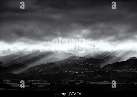 Les rayons du soleil brillent à travers les nuages de tempête à l'aube sur les contreforts et les montagnes en Guia de Isora, sur l'ouest de Tenerife, Canaries, Espagne Banque D'Images